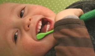 Billedet viser en baby med en tandbørste. Billedet viser en baby med en tandbørste.