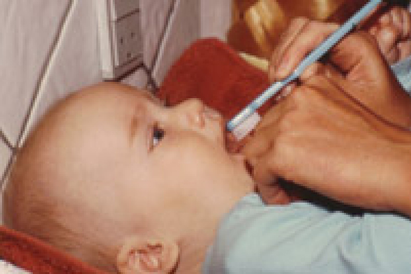 Billedet viser en baby der ligger ned og får børstet tænder.