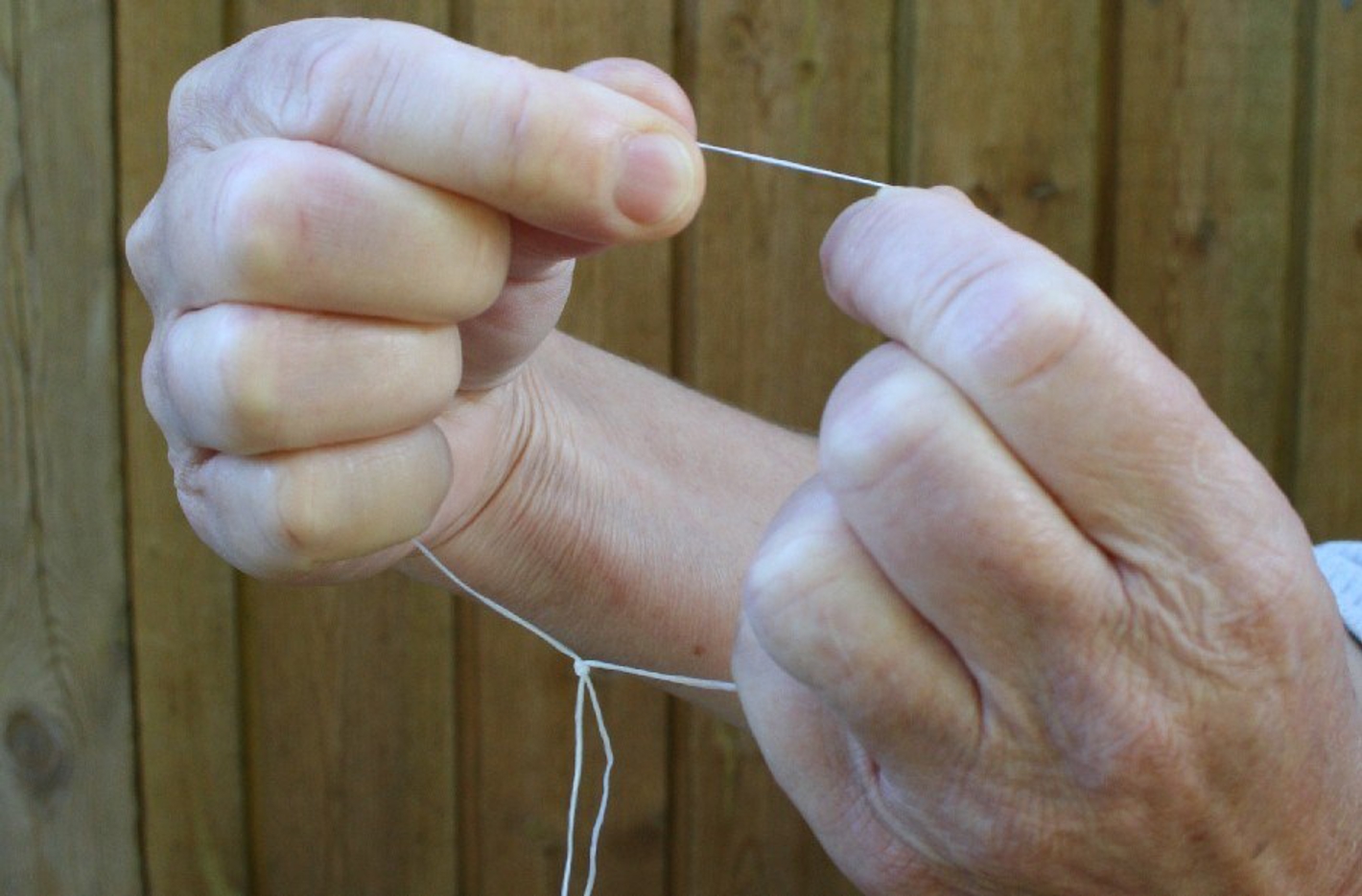 Billedet viser en der holder en ring af tandtråd mellem fingrene.
